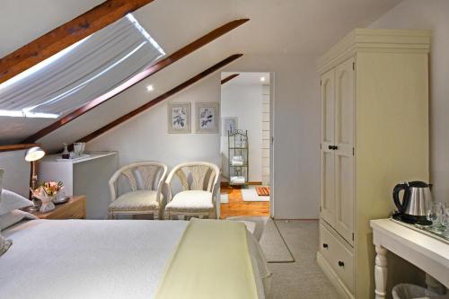 a room with a bed and two chairs in it at Centre-Ville Guest House in Franschhoek