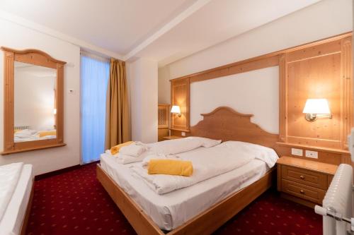 a bedroom with a large bed and a mirror at Hotel Fanes Suite & Spa in Moena