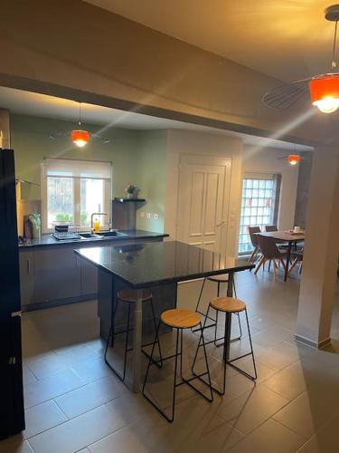 une cuisine avec une table et des tabourets dans une pièce dans l'établissement Gîte de l impasse proche europa park, à Diebolsheim