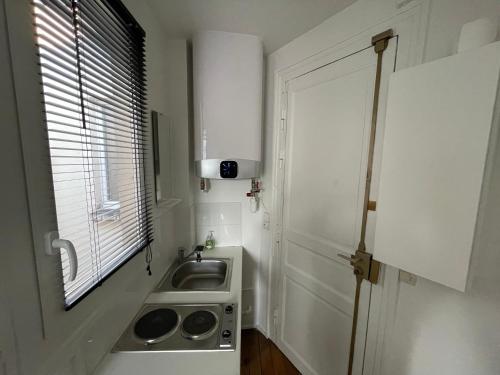 une petite cuisine avec un évier et une fenêtre dans l'établissement Studio cosy 17e Arc de Triomphe et champs Élysées, à Paris
