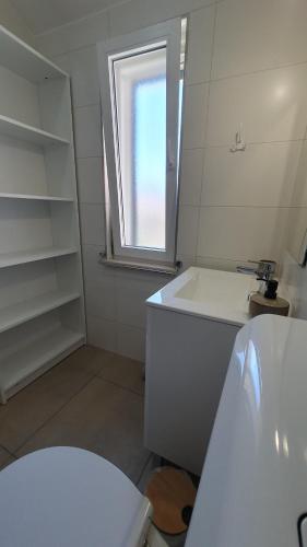 La salle de bains blanche est pourvue d'un lavabo et d'une fenêtre. dans l'établissement Holiday house - Dvori Vlahovici, à Opuzen