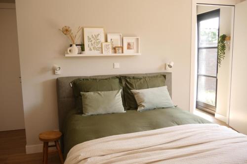 a bedroom with a bed with green sheets and a window at Bed and Breakfast t Klijnhuysje in Kaatsheuvel