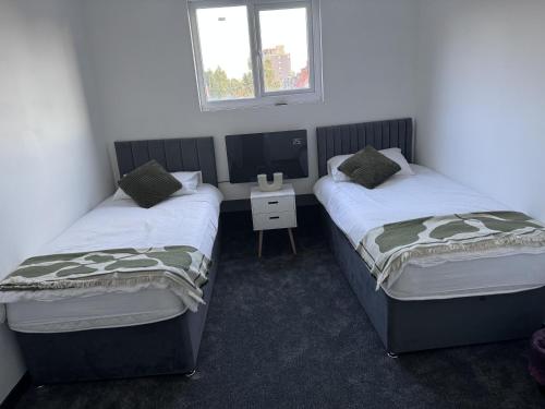 two beds in a room with a desk and a tv at City Apartment Sleeps 5 with Parking in Manchester