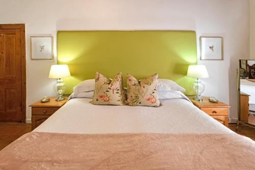 a bedroom with a large bed with a green headboard at Centre-Ville Guest House in Franschhoek