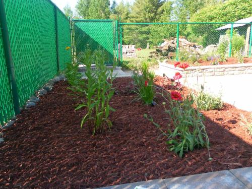 a garden with red flowers and a fence at Auberge de la Tour et Spa in Magog-Orford