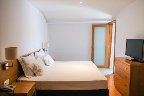 a bedroom with a bed and a television in it at Aparthotel Vouga in Termas de Sao Pedro do Sul