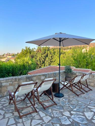 a group of chairs and a table with an umbrella at The Yard Residence in Gavalochori