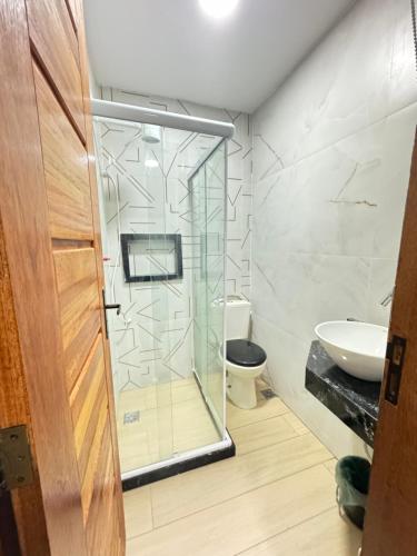 a bathroom with a glass shower and a toilet at Casa na praia in Arraial do Cabo