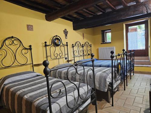 two beds in a room with yellow walls at Agrituriamo Ca Serrantonio - Ferri Appartamento Verdi in Urbania