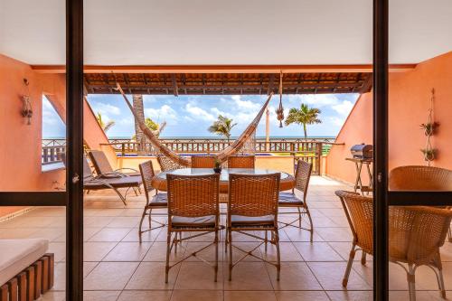 a dining room with a table and chairs on a balcony at Oceanview A102 - PÉ NA ÁREA - perto do centro, 2 dormitórios, piscina, cozinha, 116m2 in Cumbuco