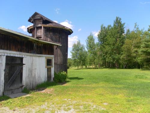 an old barn with a tower on a field at Auberge de la Tour et Spa in Magog-Orford