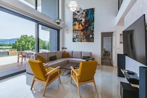 a living room with a couch and yellow chairs at HIRUNDO- villa with saunas and hot tub in Sela pri Dobovi