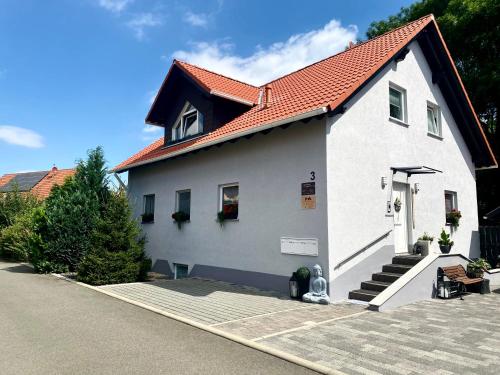 a white house with a red roof at Ferienwohnung Am Wäldchen in Erfurt