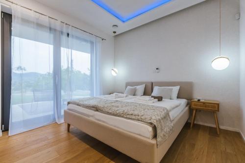 a bedroom with a large bed and a large window at HIRUNDO- villa with saunas and hot tub in Sela pri Dobovi