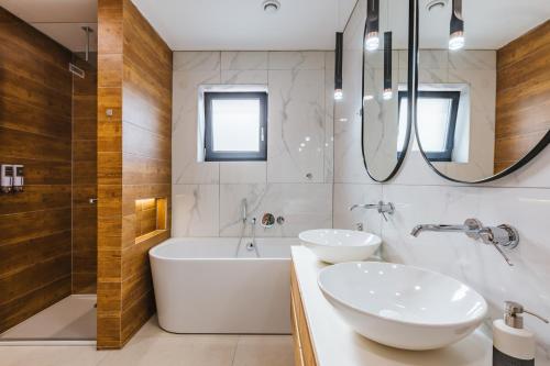 a bathroom with two sinks and a tub and shower at HIRUNDO- villa with saunas and hot tub in Sela pri Dobovi