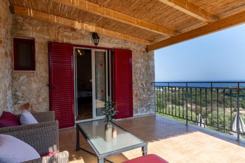 a patio with red shutters and a glass table at Villa Zoe (formerly Villa Eboros) in Ratzaklíon