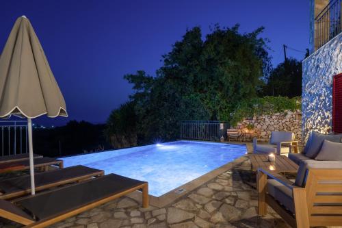a swimming pool at night with an umbrella at Villa Zoe (formerly Villa Eboros) in Ratzaklíon
