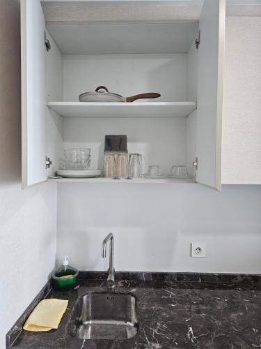 a kitchen counter with a sink and a shelf at Green Sedayu Apartment Suite by Ellison in Jakarta