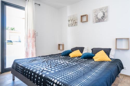 une chambre avec un lit avec des oreillers bleus et jaunes dans l'établissement Superbe villa climatisée, à Connaux