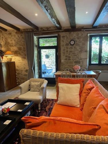 a living room with an orange couch and chairs at Lime Tree Farmhouse in Saint-Saud-Lacoussière