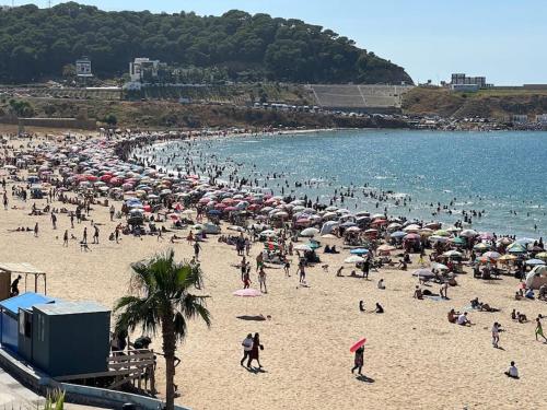 a crowd of people on a beach with umbrellas at apartamiento playa ksar sghire in Tangier