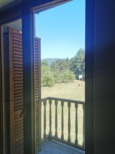 an open door to a balcony with a horse in a field at Pine corner Mojkovac in Mojkovac