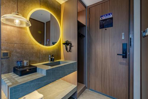 a bathroom with a sink and a mirror at Elong RuiYun Hotel Fuyang Normal University in Fuyang