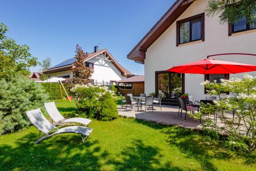 a yard with chairs and an umbrella and a house at Guest House Pasaulio Krastas in Palanga
