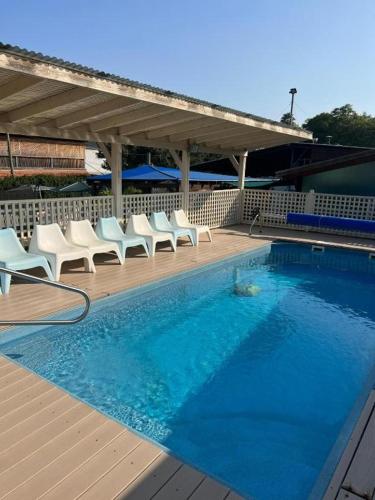 a swimming pool with white chairs next to a deck at בית הזורע של רשת לב הגולן - 4 צימרים מדהימים עם בריכה משותפת ליד הכנרת in Menaẖemya