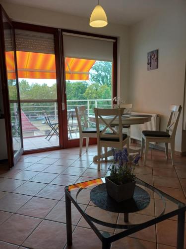 a living room with a table and chairs and a balcony at Sári Apartman in Siófok