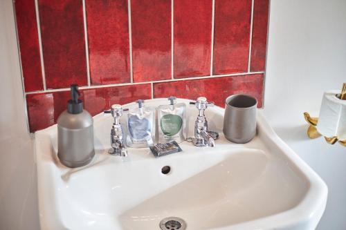 a bathroom sink with a soap dispenser and cups on it at Hideaway in Amble