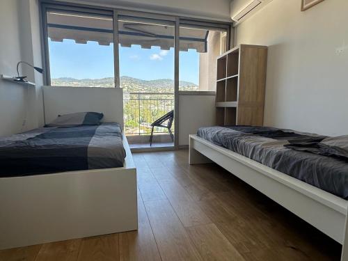 une chambre avec un lit et une grande fenêtre dans l'établissement Appartement T3 de Standing vue Mer et Marina, à Mandelieu-la-Napoule