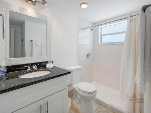 a bathroom with a sink and a toilet and a mirror at 2BR Near The Beach !Walk 2 Everything! in West Palm Beach
