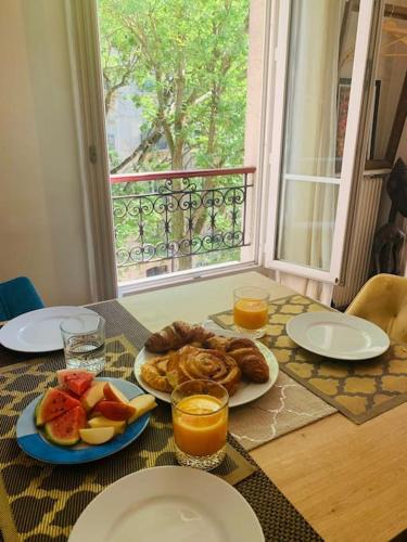 une table avec une assiette de nourriture et du jus d'orange dans l'établissement Appartement Haussmanien au coeur du village Montmartre !, à Paris