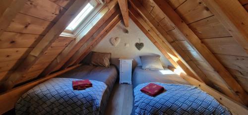 Cette chambre mansardée comprend 2 lits jumeaux et une fenêtre. dans l'établissement Profiter en Famille au Viscos., à Geu