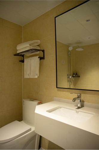 a bathroom with a sink and a mirror and a toilet at Elong Me Hotel Fuyang Wanda Plaza South Bus Station in Fuyang