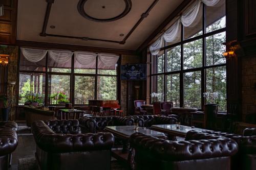 a restaurant with leather chairs and tables and windows at Maxi Park Hotel & Spa in Velingrad