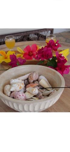a bowl filled with shells and flowers on a table at Ogumka 2 , self catering , Santa Maria , Mahe , Seychelles in Anse Royale