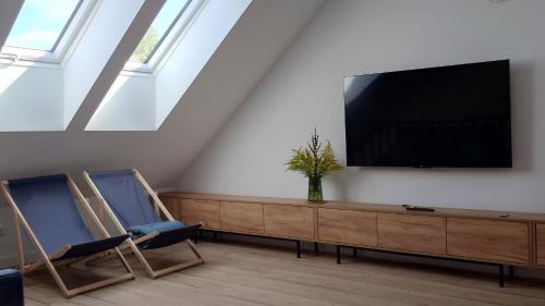 a living room with a flat screen tv and two chairs at Bukowska House in Sulechów