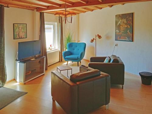 a living room with a couch a chair and a tv at BnB Het Geluk van Limburg in Mechelen