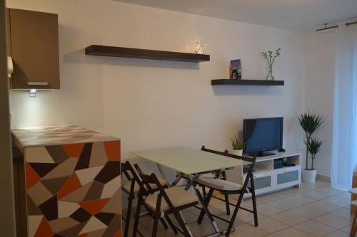 une cuisine avec une table et des chaises et une télévision dans l'établissement T2 avec terrasse proche commerces et plages, à Anglet