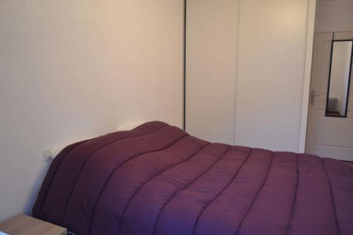 - un lit avec une couverture violette dans l'établissement T2 avec terrasse proche commerces et plages, à Anglet