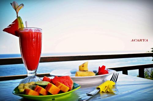 a table with a plate of fruit and a drink at Acarya Bungalows Amed in Amed