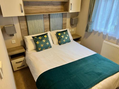 a small bedroom with a bed with two pillows at 3 Bedroom Caravan MC37, Shanklin, Isle of Wight in Shanklin
