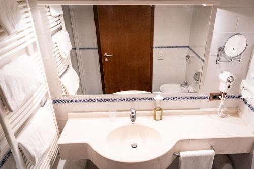 a white bathroom with a sink and a mirror at PanoramaHotel Penegal in Mendola