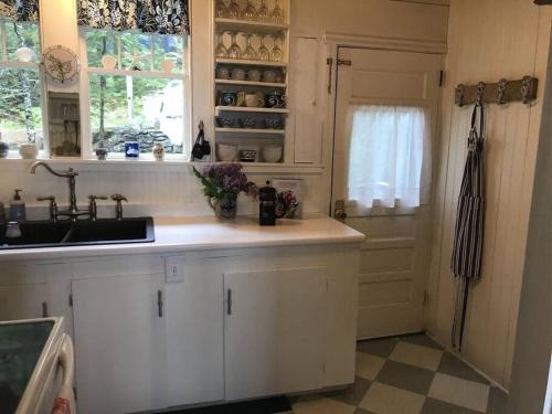 una cucina con mobili bianchi, un lavandino e una finestra di Compass Rose a Boothbay Harbor