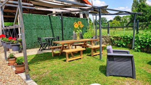 a picnic table under a pergola in a garden at A 2 pas d AZAY in Neuil