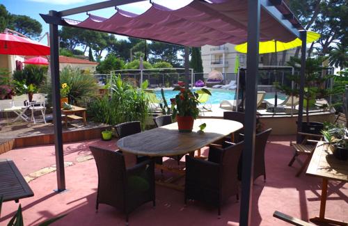 a patio with a table and chairs under an umbrella at B&B Val D'azur in Carqueiranne