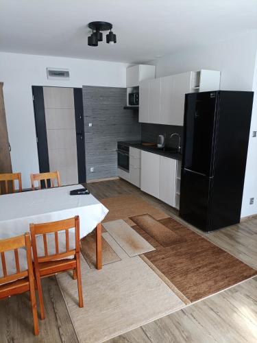 een keuken met een tafel en een zwarte koelkast bij Apartament Przylesie in Stężyca