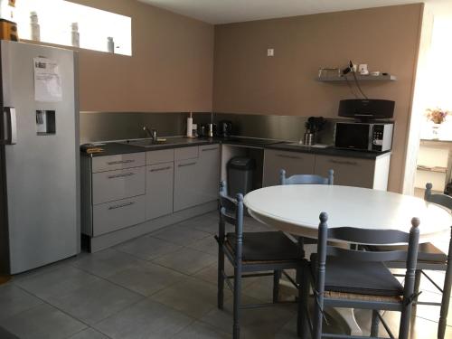 une cuisine avec une table et un réfrigérateur blanc dans l'établissement Gîte La Laiterie, à Wanquetin